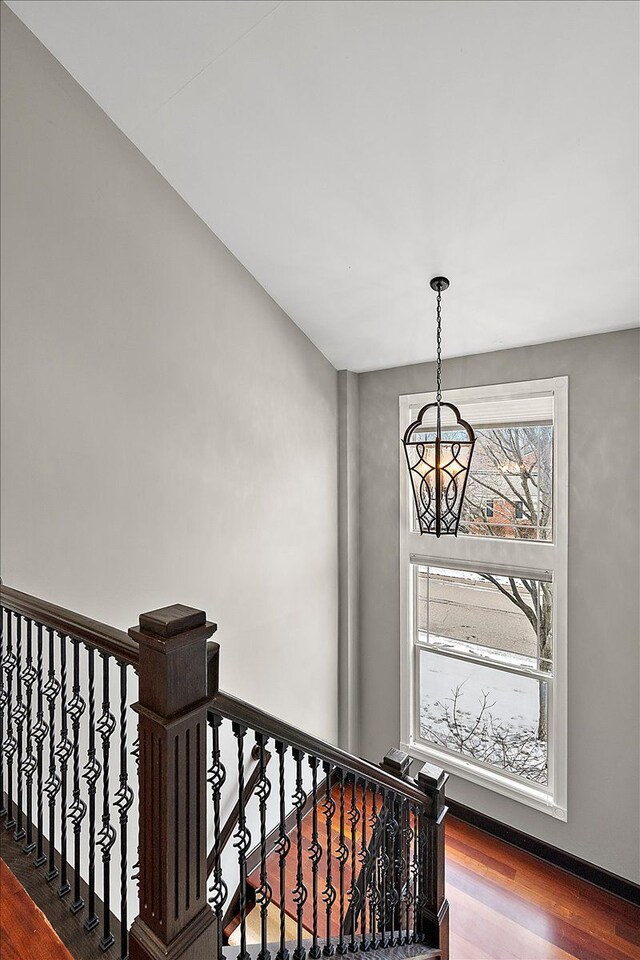 staircase featuring a notable chandelier and wood finished floors