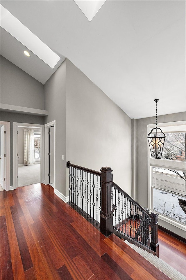 hallway with a skylight, recessed lighting, an upstairs landing, wood finished floors, and baseboards