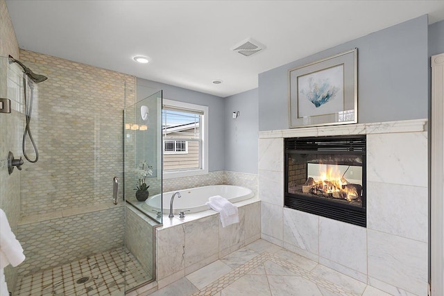 bathroom featuring a stall shower, a garden tub, a fireplace, and visible vents