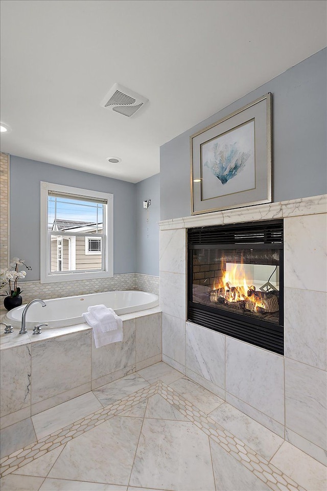 bathroom featuring a bath, a fireplace, and visible vents