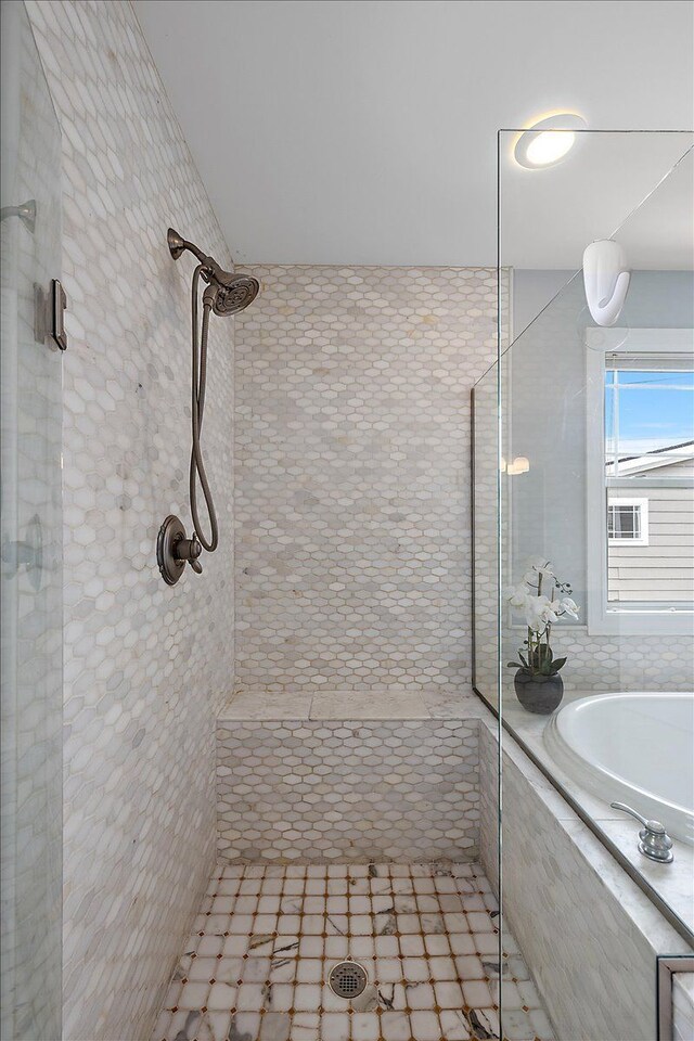 full bath with tiled shower and a bath