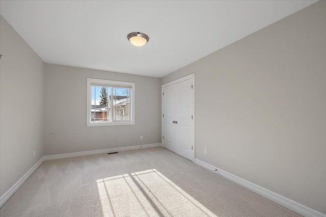 unfurnished bedroom featuring light carpet, visible vents, and baseboards