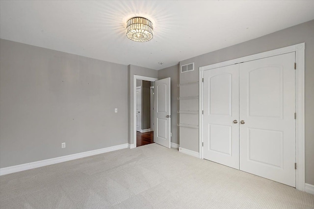 unfurnished bedroom featuring light carpet, baseboards, visible vents, and a closet