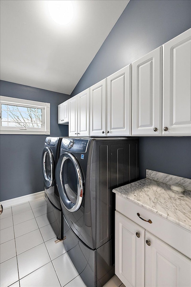 washroom with light tile patterned floors, separate washer and dryer, cabinet space, and baseboards