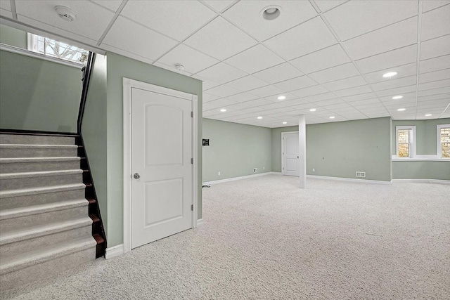 below grade area with carpet floors, a paneled ceiling, recessed lighting, baseboards, and stairs