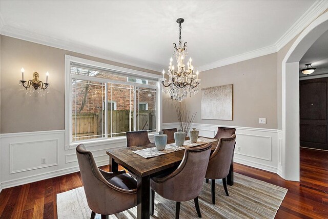 dining area featuring arched walkways, wainscoting, a notable chandelier, and wood finished floors