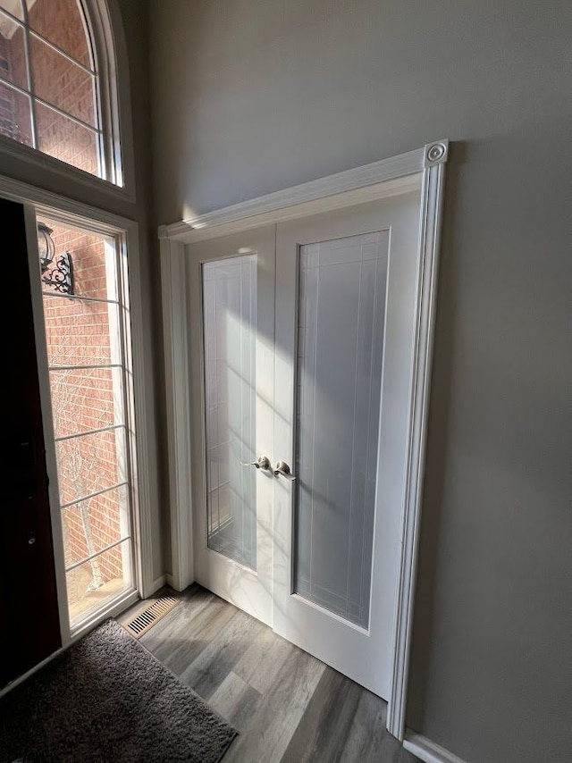 doorway with french doors, visible vents, and wood finished floors