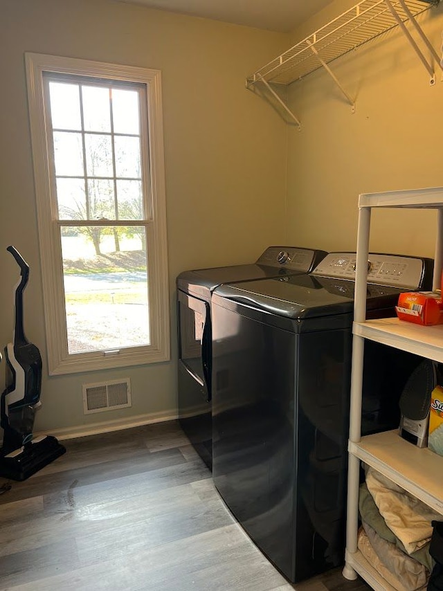 washroom featuring laundry area, visible vents, washer and clothes dryer, and wood finished floors