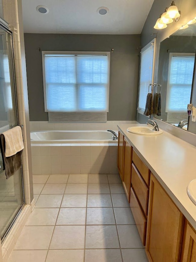 full bath with double vanity, a garden tub, a sink, and tile patterned floors