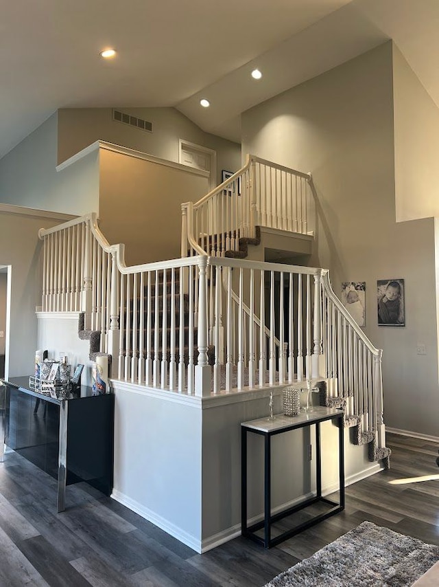 stairway with high vaulted ceiling, visible vents, wood finished floors, and recessed lighting