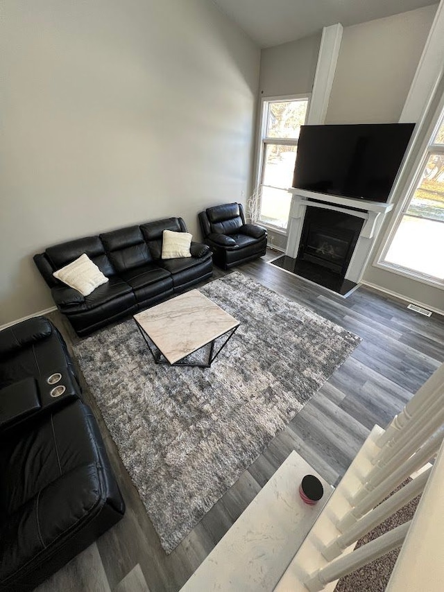 living room with dark wood-style floors, visible vents, a fireplace, and baseboards