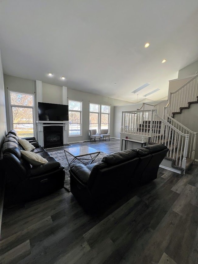 living area with dark wood-style flooring, a healthy amount of sunlight, a fireplace, and stairs