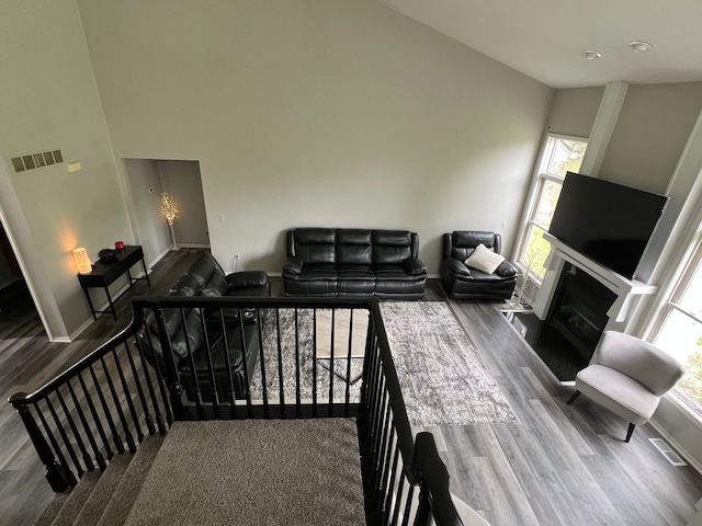 119 Prestwick Trl, Highland, MI 48357 - living area featuring wood finished floors, a glass covered fireplace, a high ceiling, and baseboards