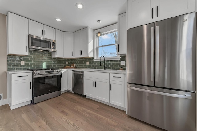 kitchen with sink, white cabinetry, decorative light fixtures, and appliances with stainless steel finishes