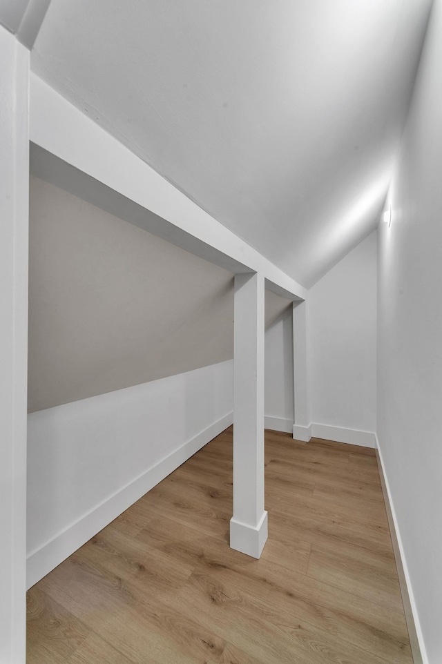 additional living space with light wood-type flooring and vaulted ceiling