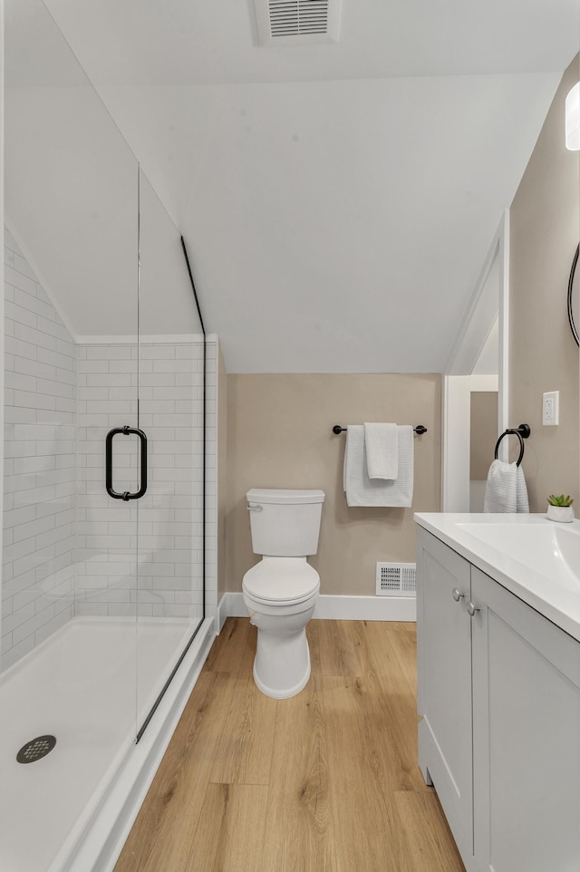 bathroom with a shower with shower door, hardwood / wood-style floors, vanity, and lofted ceiling