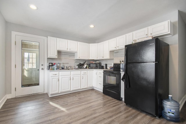 kitchen featuring black appliances, white cabinetry, decorative backsplash, sink, and hardwood / wood-style flooring