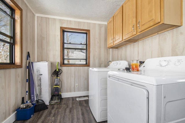 clothes washing area with a textured ceiling, cabinets, dark hardwood / wood-style floors, wood walls, and independent washer and dryer