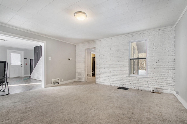 carpeted empty room with brick wall and crown molding