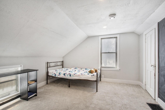 carpeted bedroom with vaulted ceiling and a textured ceiling