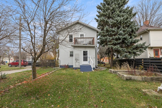 back of house with a balcony and a lawn