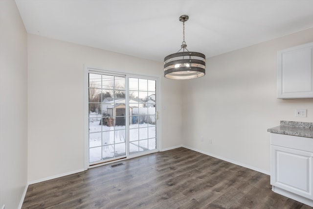 unfurnished dining area with a chandelier and dark wood-type flooring