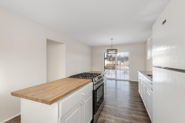 kitchen with white cabinets, stainless steel gas range, a center island, decorative light fixtures, and white fridge