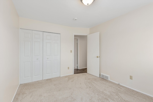 unfurnished bedroom featuring a closet and light carpet