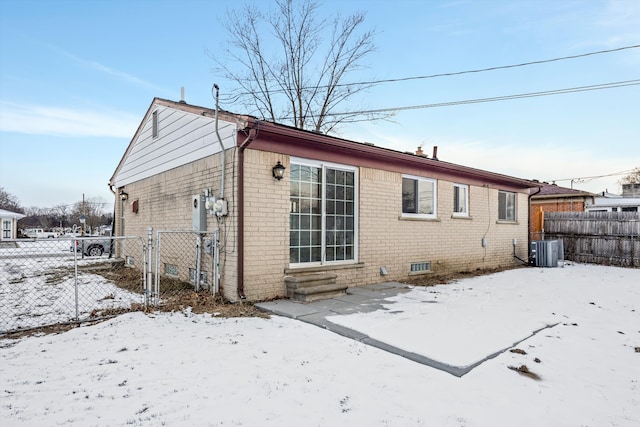 snow covered back of property featuring central air condition unit