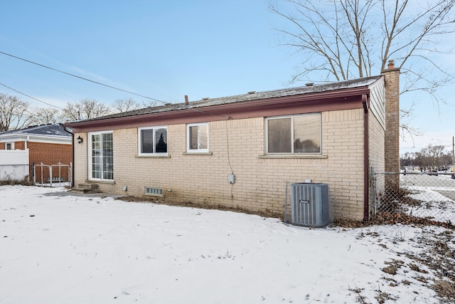 snow covered back of property featuring cooling unit