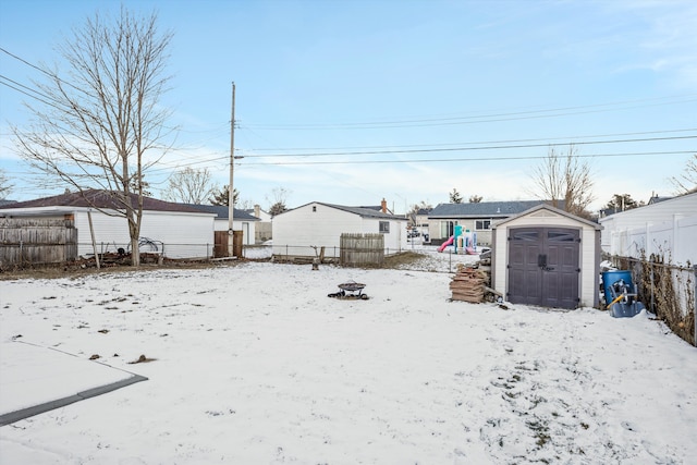 yard layered in snow featuring a playground and a storage unit