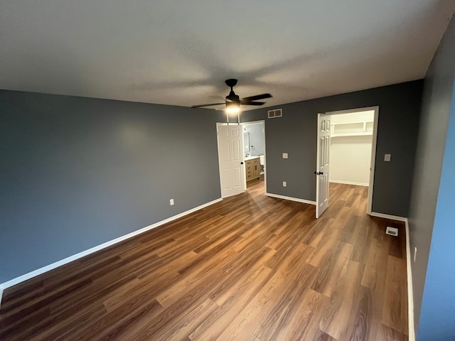 unfurnished bedroom with hardwood / wood-style flooring, ceiling fan, a spacious closet, and a closet