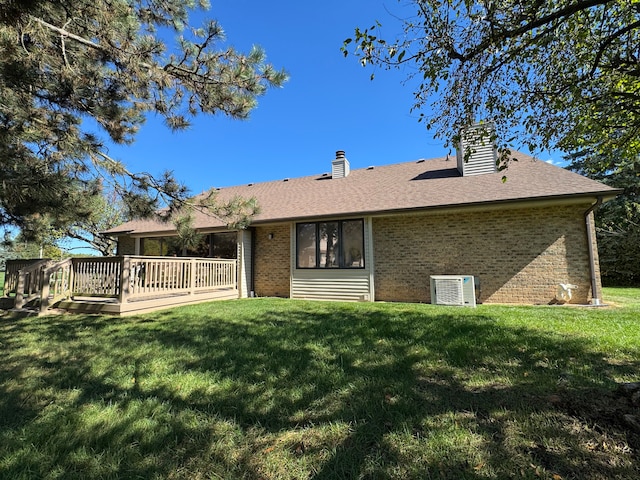 rear view of property with a lawn, central air condition unit, and a deck