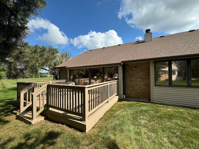 back of property featuring a wooden deck and a lawn