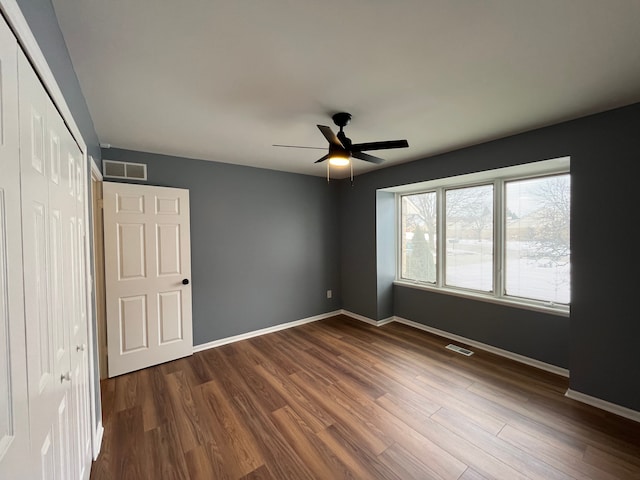 unfurnished bedroom featuring dark hardwood / wood-style floors, a closet, and ceiling fan