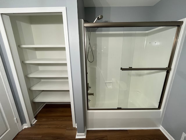 bathroom with hardwood / wood-style floors and bath / shower combo with glass door