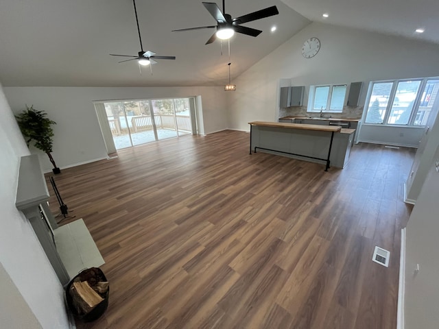 unfurnished living room featuring high vaulted ceiling, dark hardwood / wood-style floors, and ceiling fan