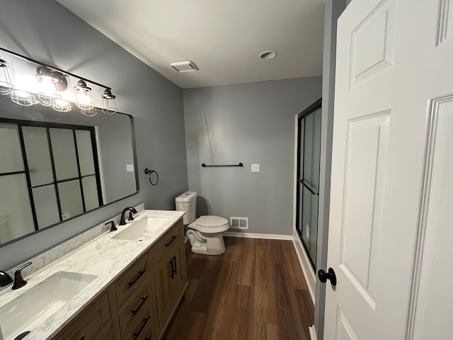 bathroom with wood-type flooring, toilet, an enclosed shower, and vanity