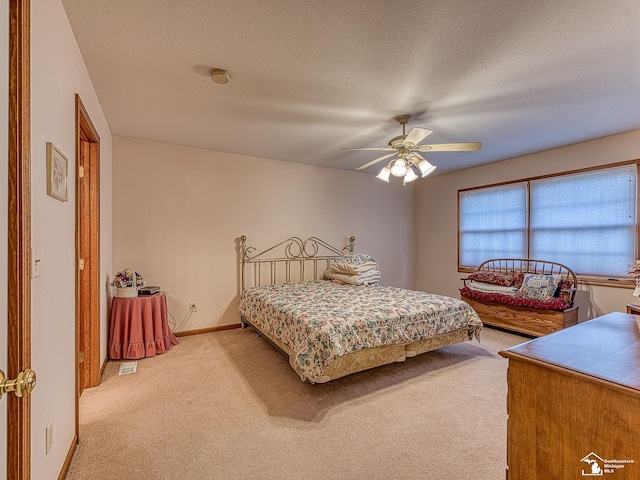 carpeted bedroom featuring ceiling fan and a textured ceiling