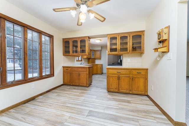 kitchen featuring sink, light hardwood / wood-style floors, tasteful backsplash, and ceiling fan