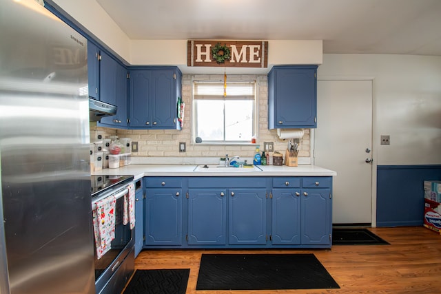 kitchen with sink, light hardwood / wood-style flooring, blue cabinets, and appliances with stainless steel finishes