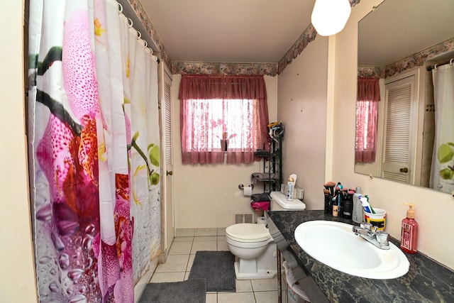 bathroom with toilet, vanity, and tile patterned flooring