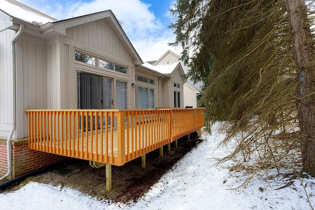 snow covered rear of property with a wooden deck