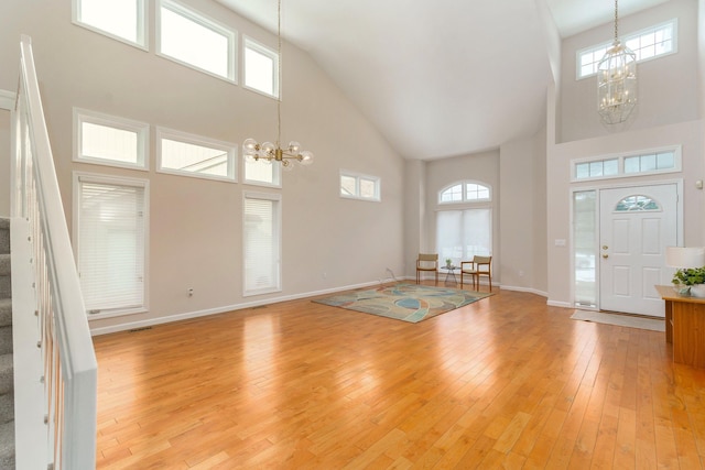 entrance foyer featuring a towering ceiling, light hardwood / wood-style flooring, and a notable chandelier