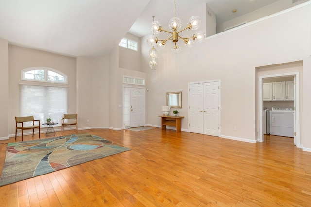 entryway with a notable chandelier, a high ceiling, light hardwood / wood-style flooring, and separate washer and dryer