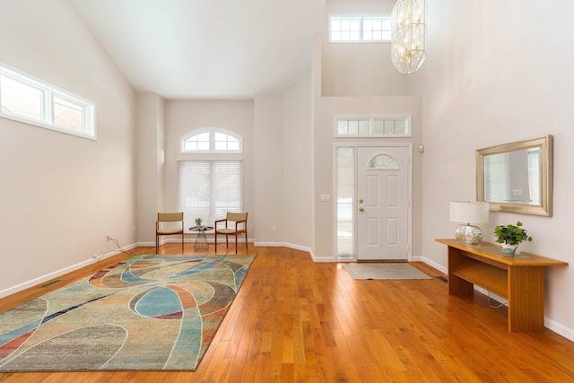 foyer entrance with a notable chandelier, a towering ceiling, and hardwood / wood-style floors