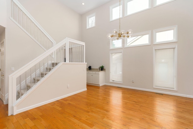 entryway featuring a chandelier, a towering ceiling, and light wood-type flooring