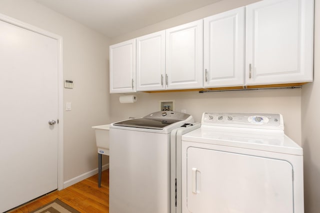 laundry area with wood-type flooring, cabinets, and washer and dryer