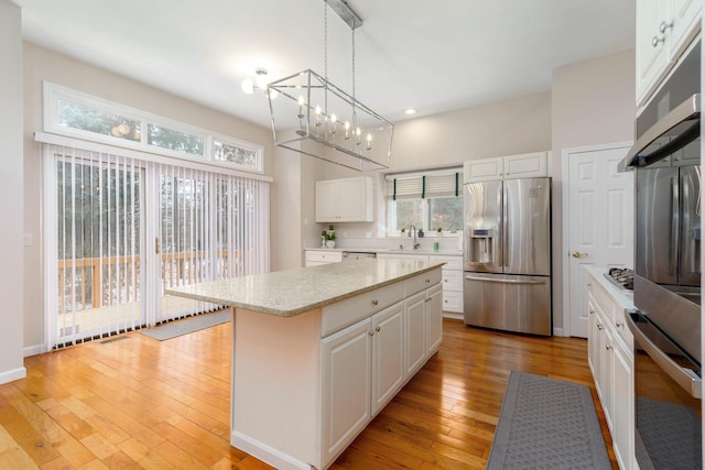 kitchen featuring pendant lighting, white cabinetry, appliances with stainless steel finishes, and a center island