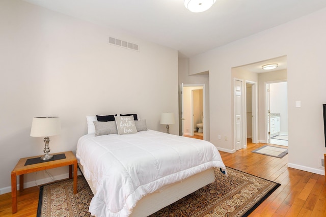 bedroom with hardwood / wood-style flooring and connected bathroom